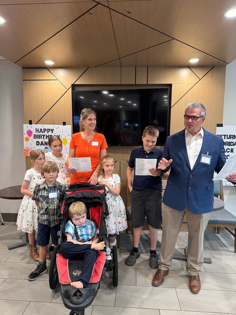 Group of children and adults at indoor event, adults presenting certificates to kids in modern venue with decorative ceiling